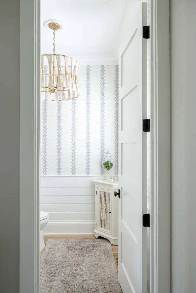 Powder room with botanical striped wallpaper and brass chandelier in Charleston, SC
