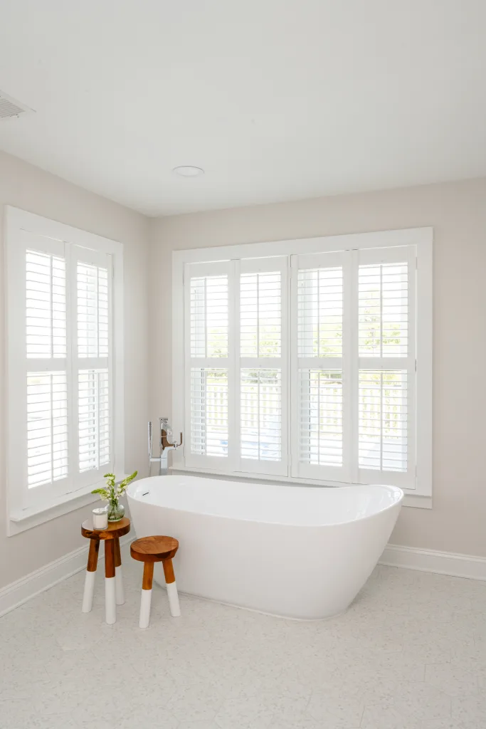 Freestanding soaking tub with plantation shutters by Charleston, SC interior designer