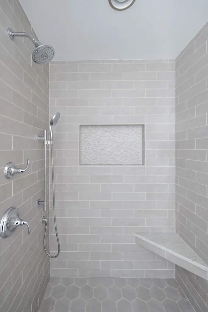 Subway tile walk-in shower with tile niche and hex floor by Charleston designer